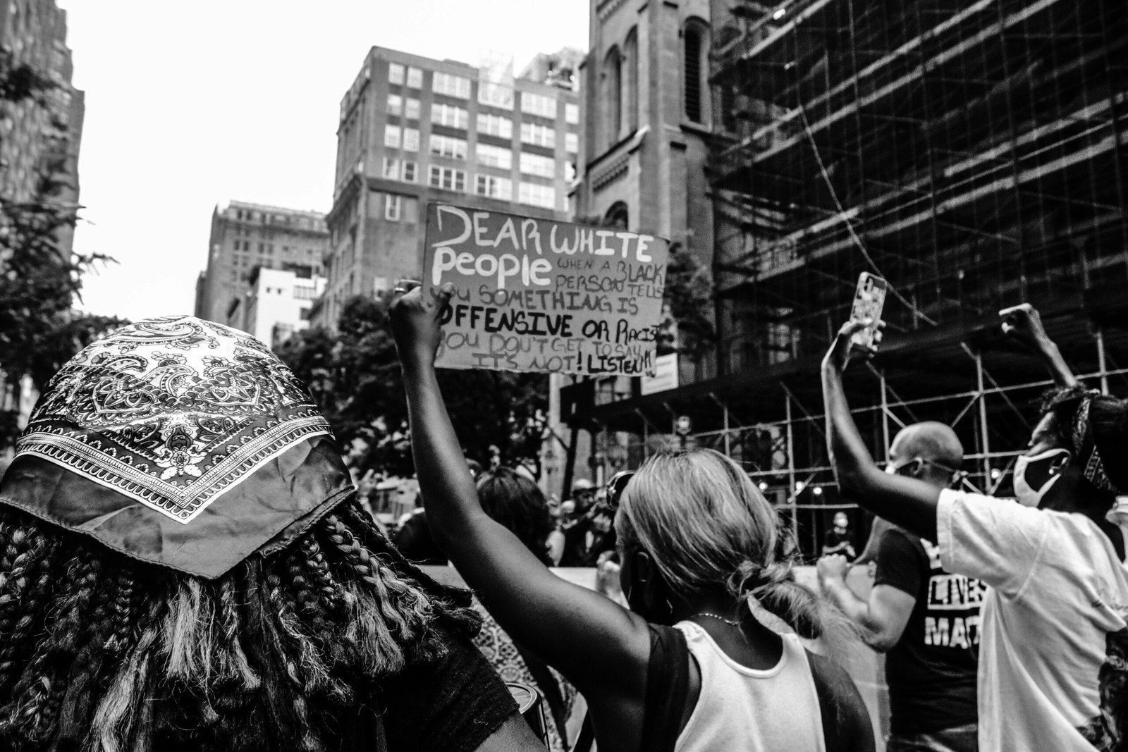 grayscale photo of people raising hands