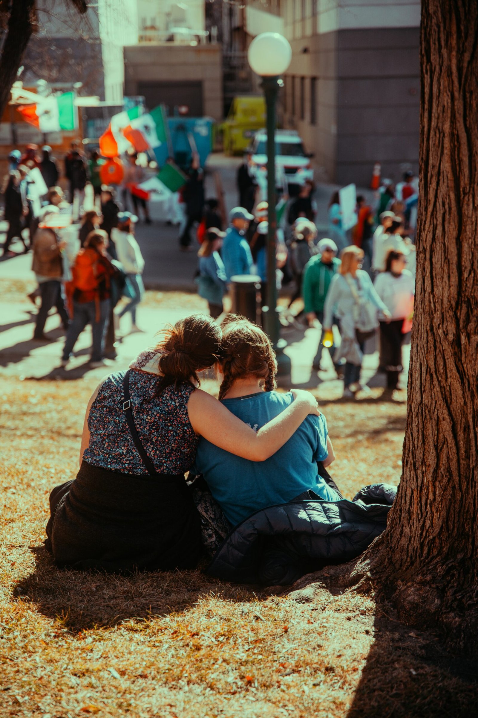 Two friends watch a crowd from the grass.