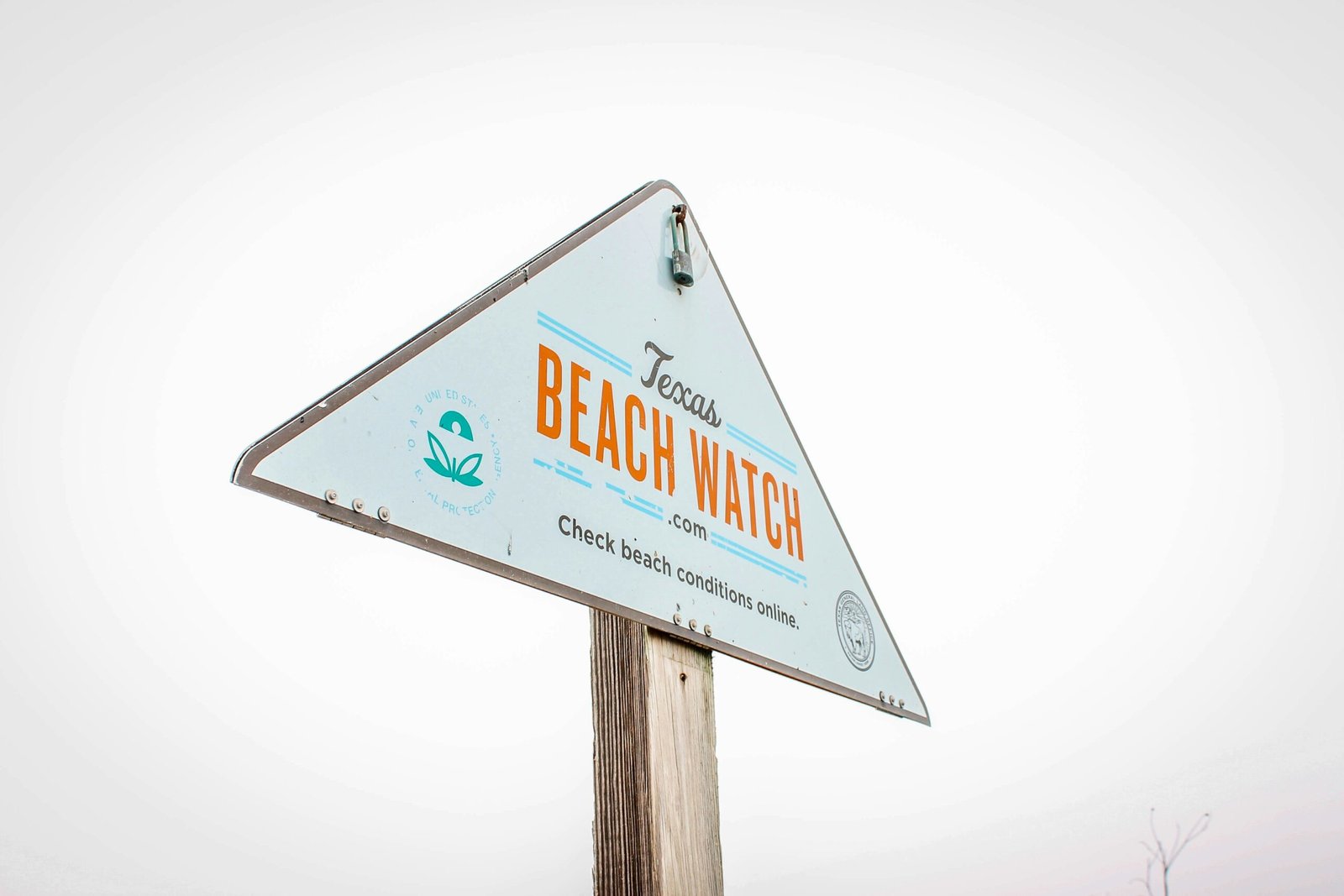 a beach watch sign on top of a wooden pole